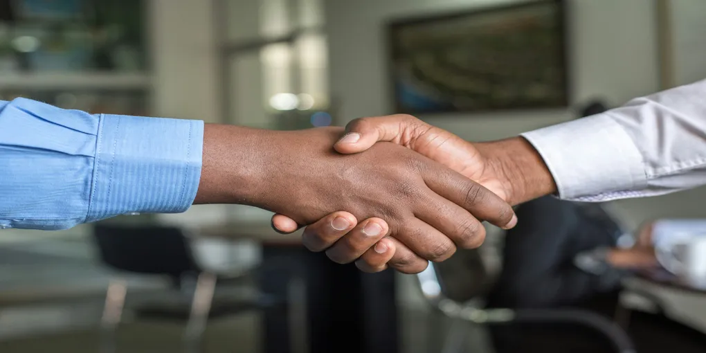 Two people shaking their hands in an apparent deal.