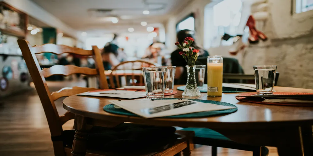 A nicely set table with a few people sitting in the background.