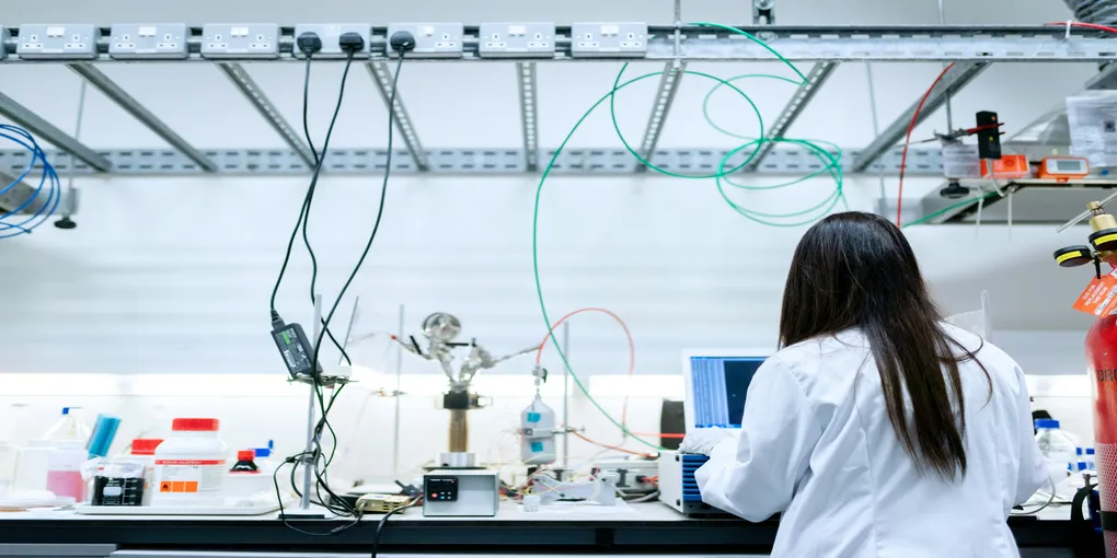 Long-haired woman in a lab setting conducting an experiment.